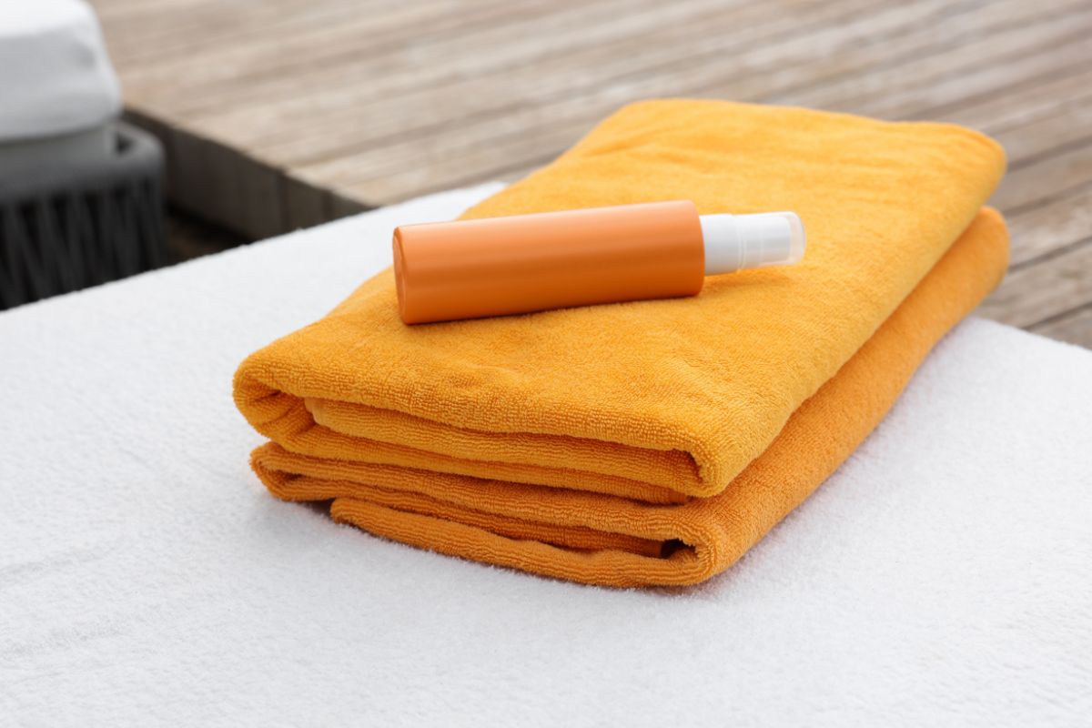 Folded orange towels and a bottle of sunscreen on a poolside lounge at Ridge Waters Waterpark.