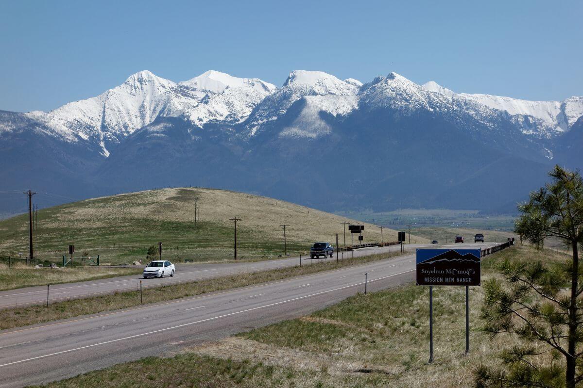 A scenic highway leading towards snow-capped mountains under a clear blue sky in Montana.