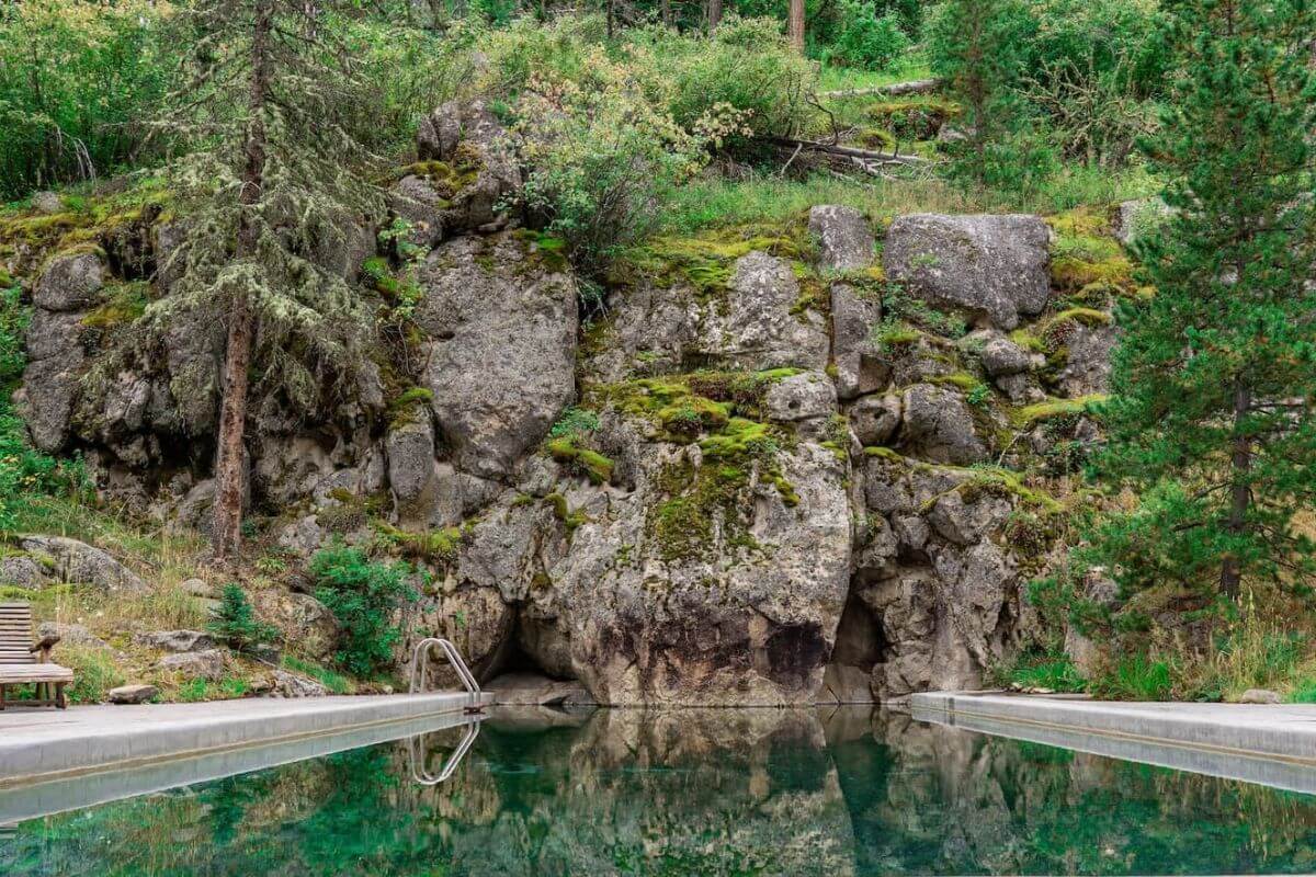 The Potosi Hot Springs pool, surrounded by trees and a natural rock formation





