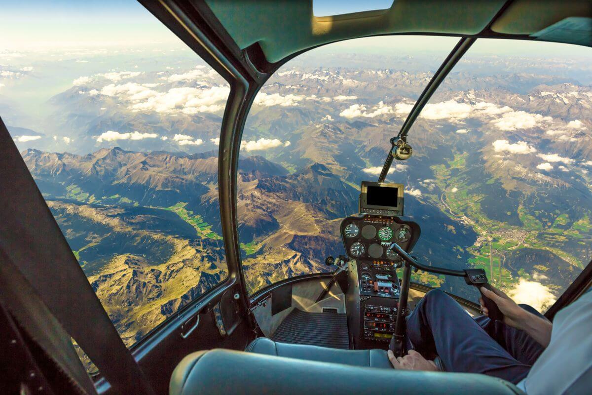 A pilot's view from the cockpit during one of Montana's premier helicopter tours, displaying rugged mountainous terrain below.