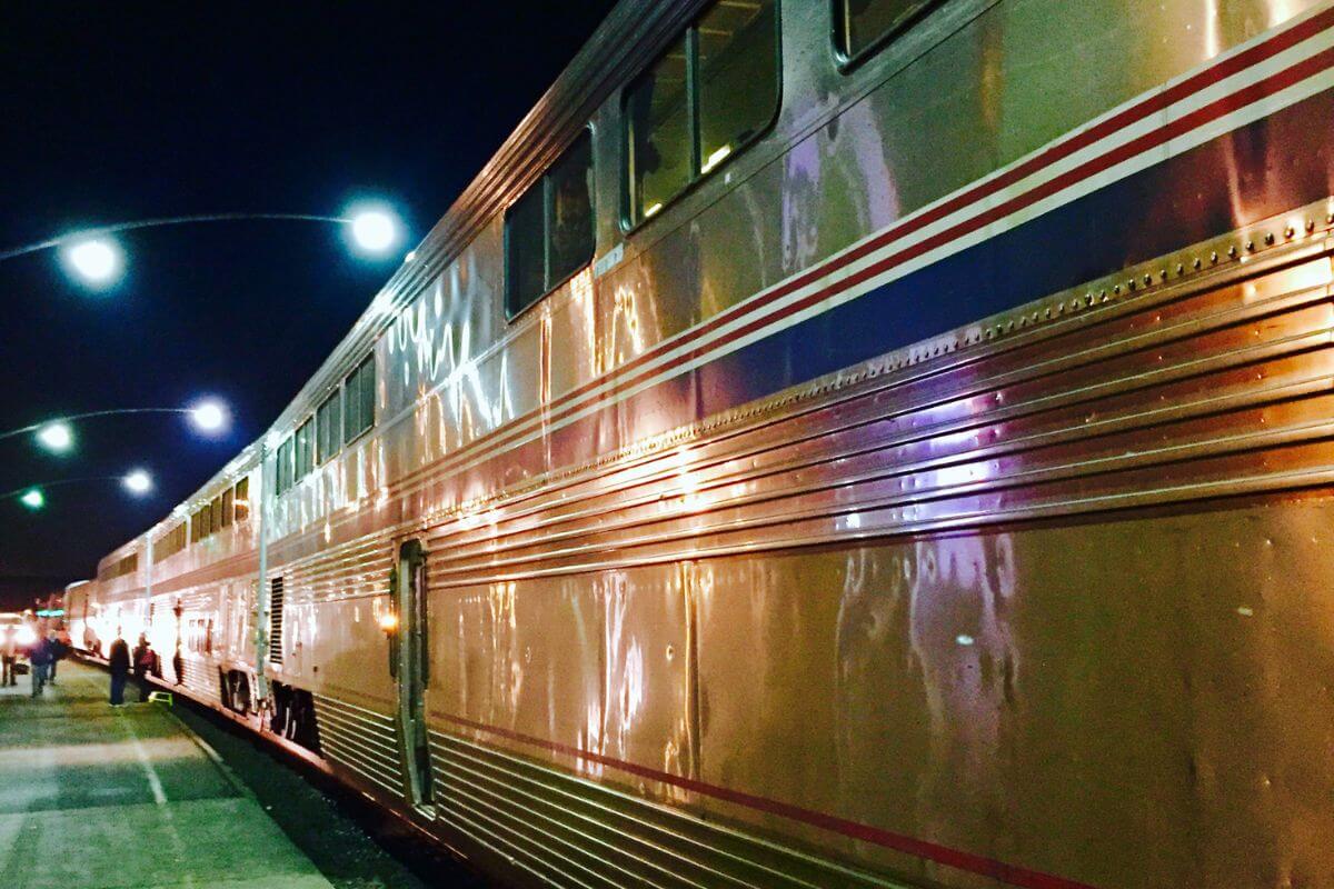 A gleaming train at a station under a night sky, ready for a Montana train tour.