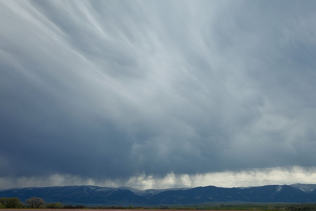 Storm clouds over a field with mountains in the background, evoking a sense of Montana's dramatic weather.