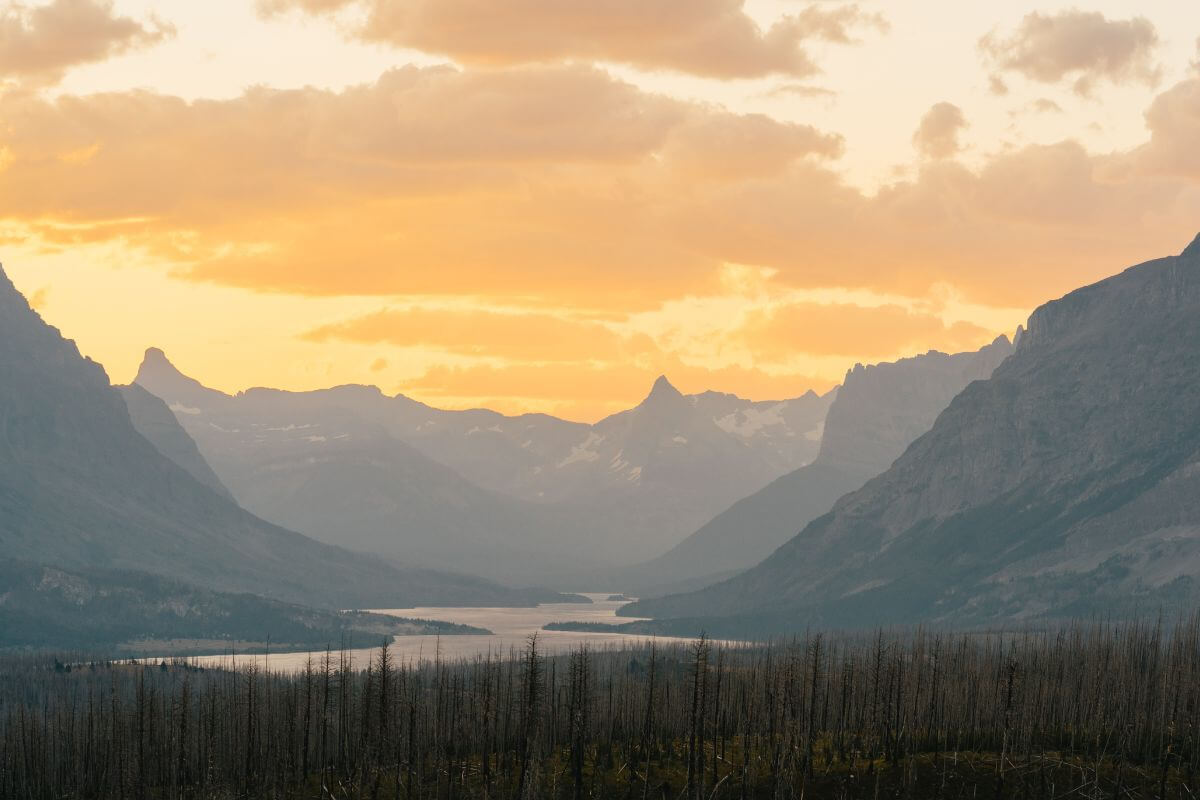 The sun is setting over the mountains in Glacier National Park.