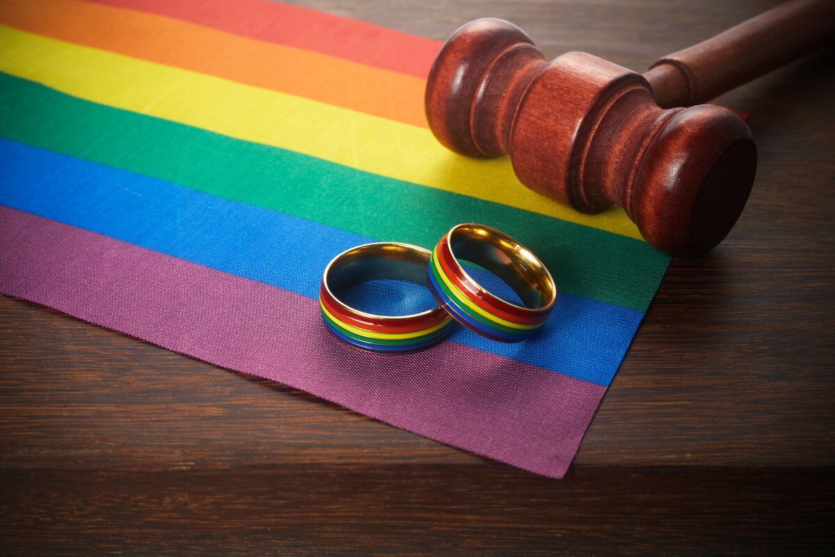 Two wedding rings and a gavel on a rainbow flag