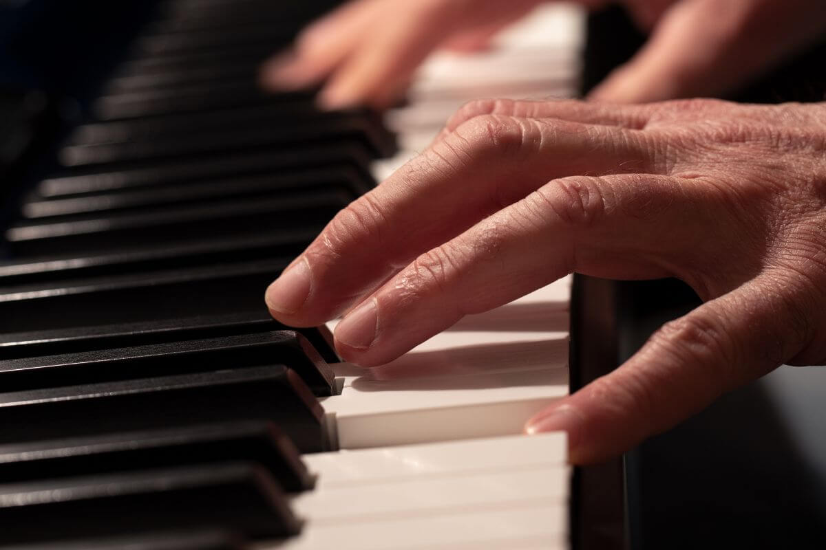 A Close up of a Person’s Hands Playing the Montana State Song on a Piano.