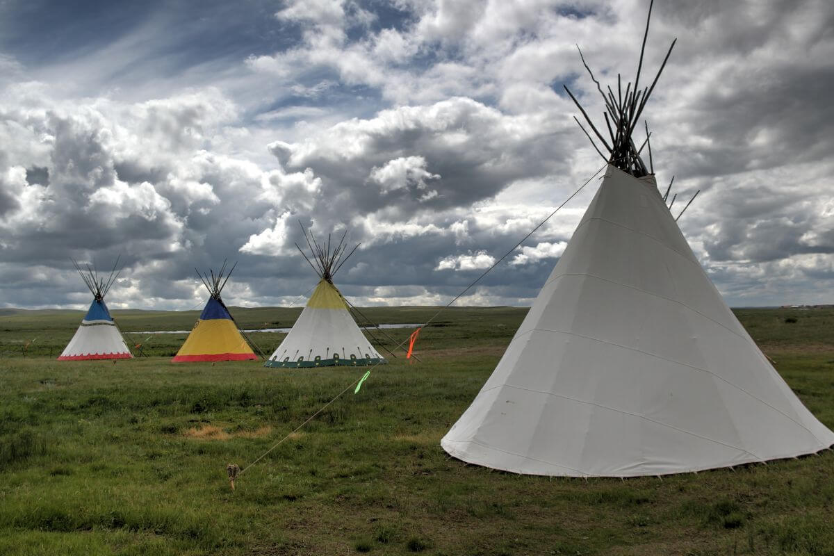 Teepees standing in a field under a cloudy sky in Montana.