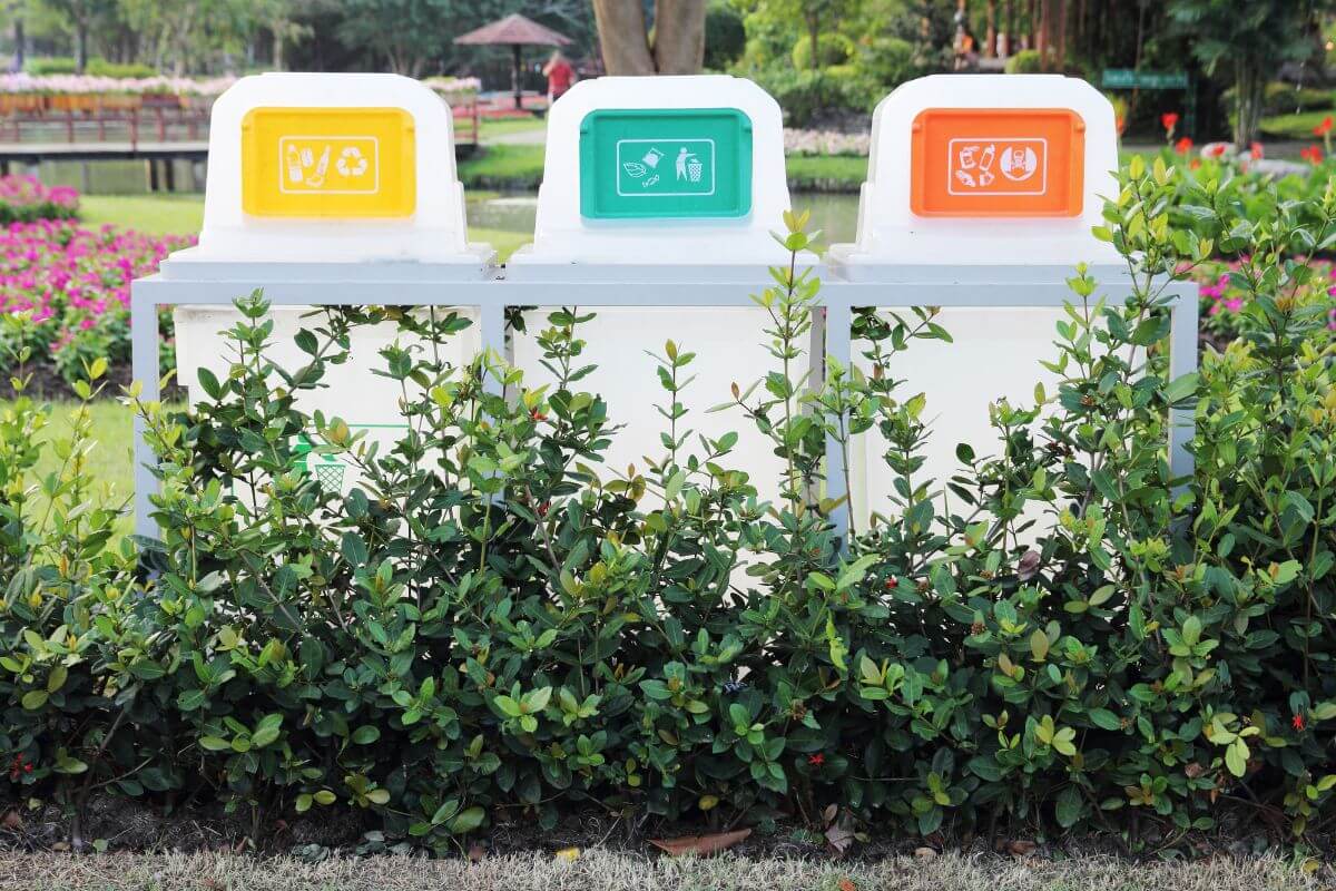 Three colorful recycling bins in a park