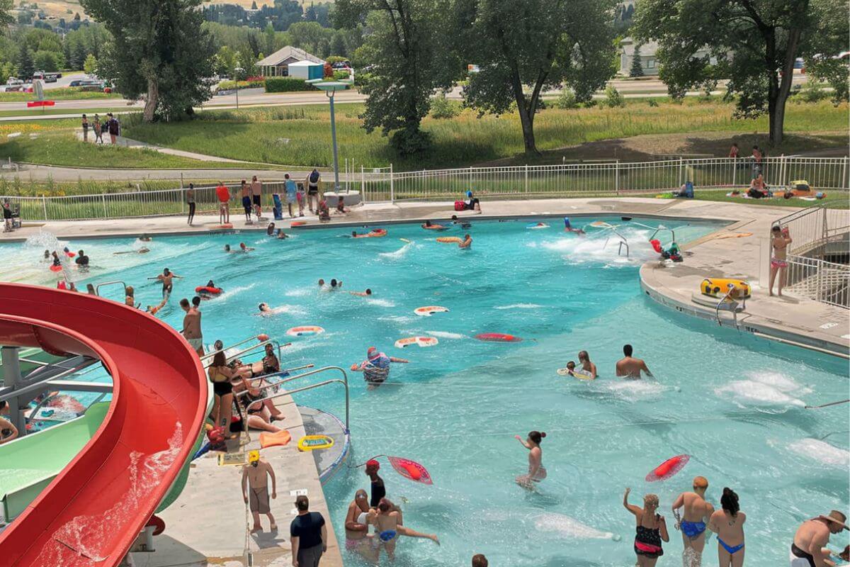People enjoy a large swimming pool with a water slide at Ridge Waters Waterpark.