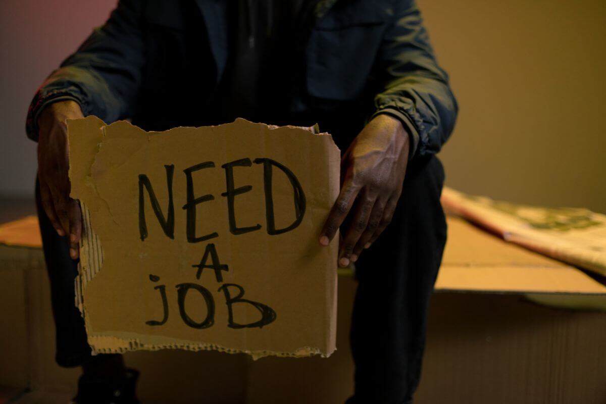 A man holding a sign that says need a job