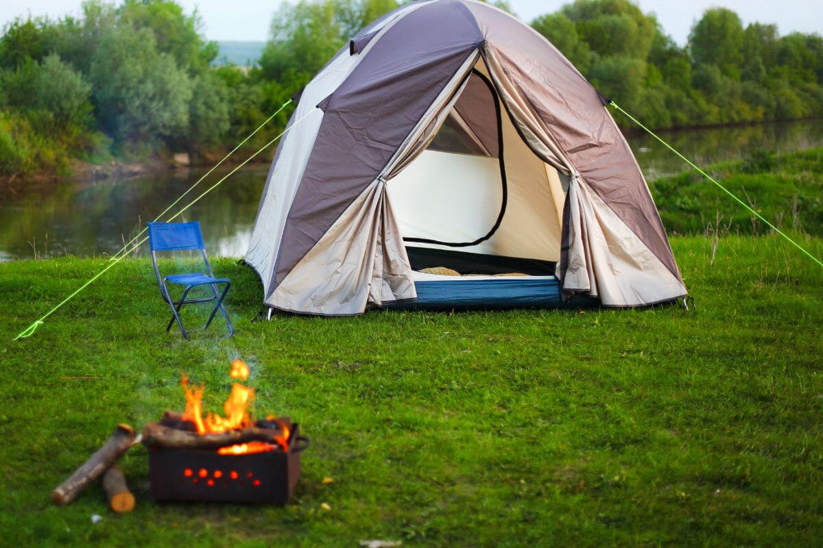 A tent and small fire area are set up near one of the lush established camping grounds close to Knowles Falls.
