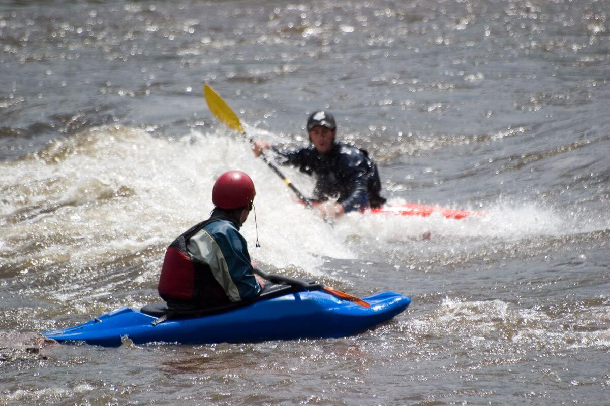 Two people in kayaks paddling their way through river rapids in Montana.