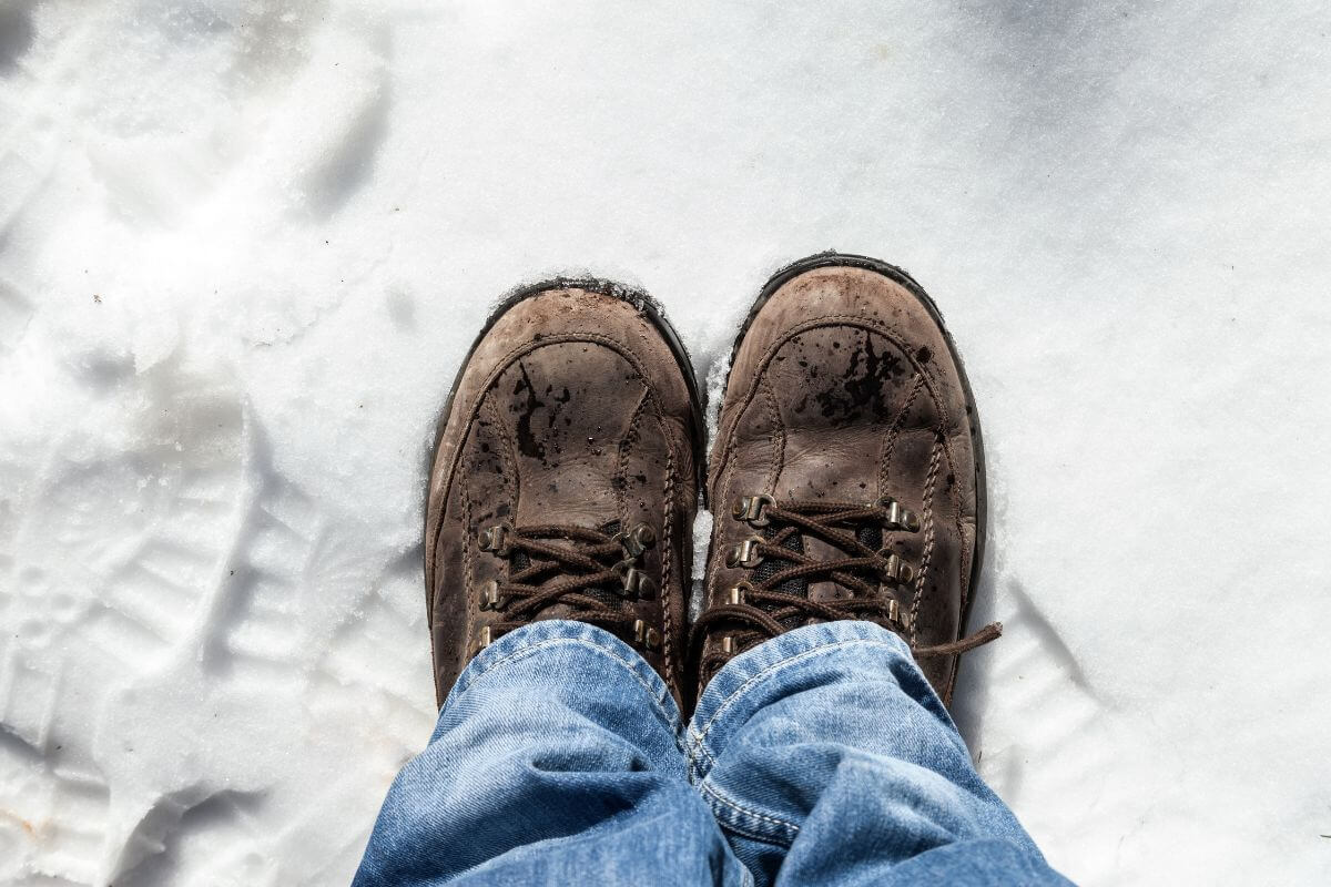 A man wears worn winter boots in the snow in Montana