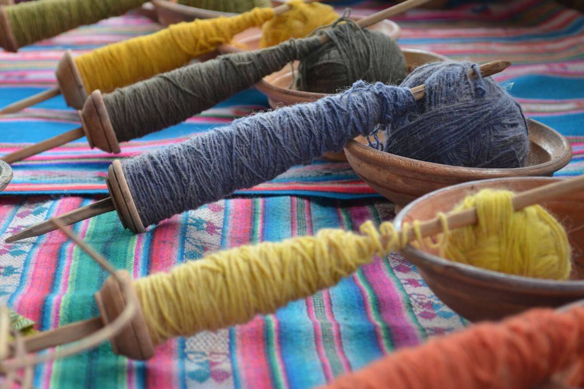 Colorful Montana alpaca yarn spools placed on a vibrant woven textile.