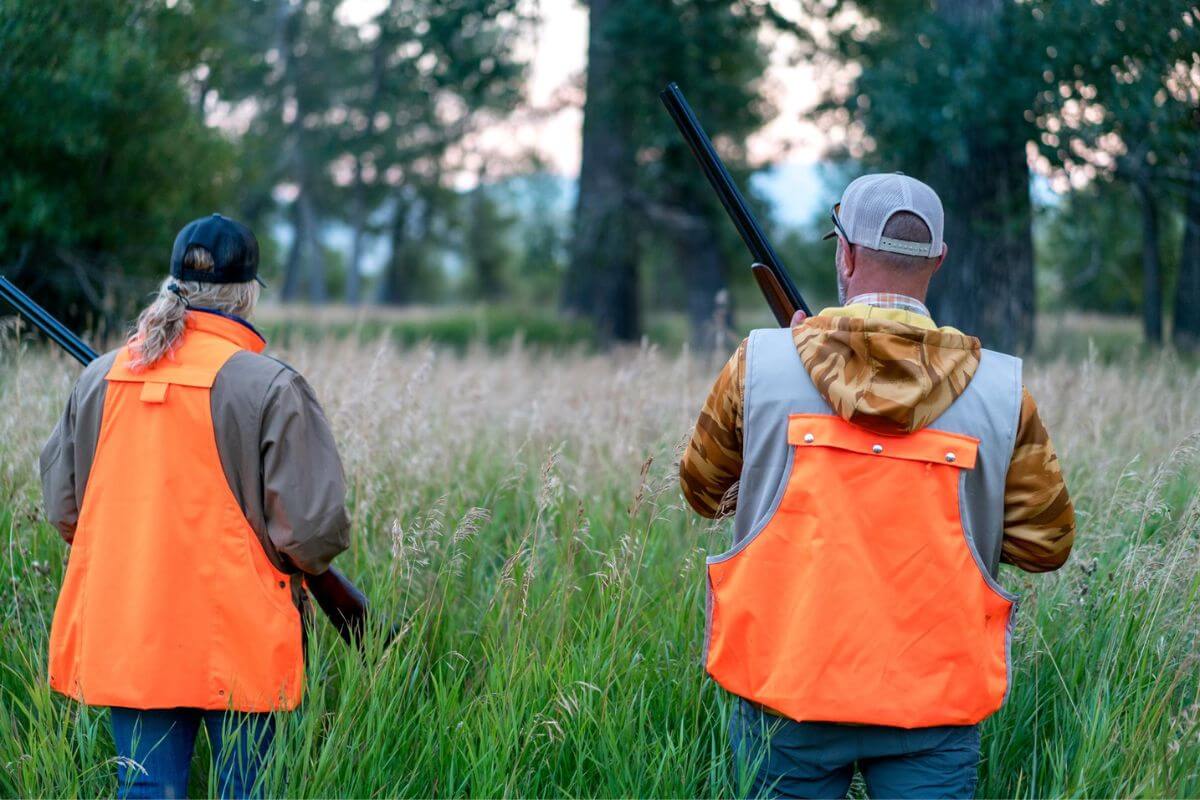 Hunters in orange vests carrying guns on a guided duck hunting adventure with the Silver Bow Club