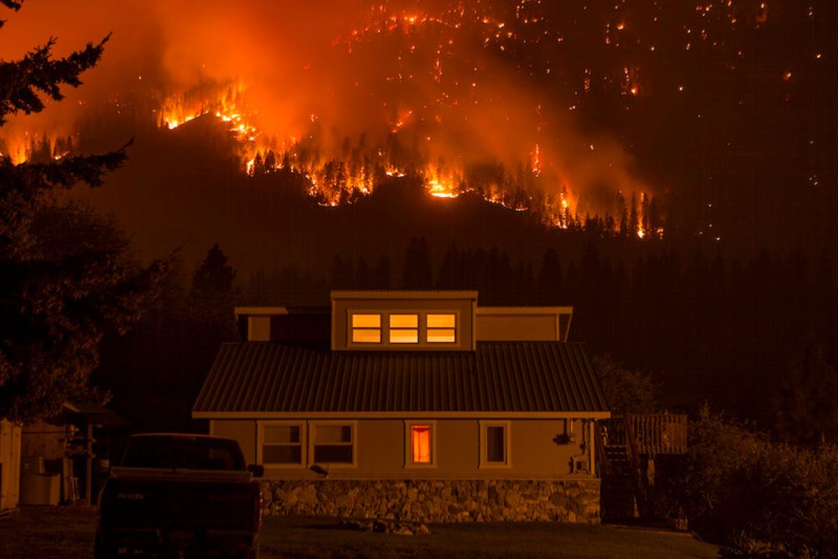 A fire rages through the forest behind a house in Montana.
