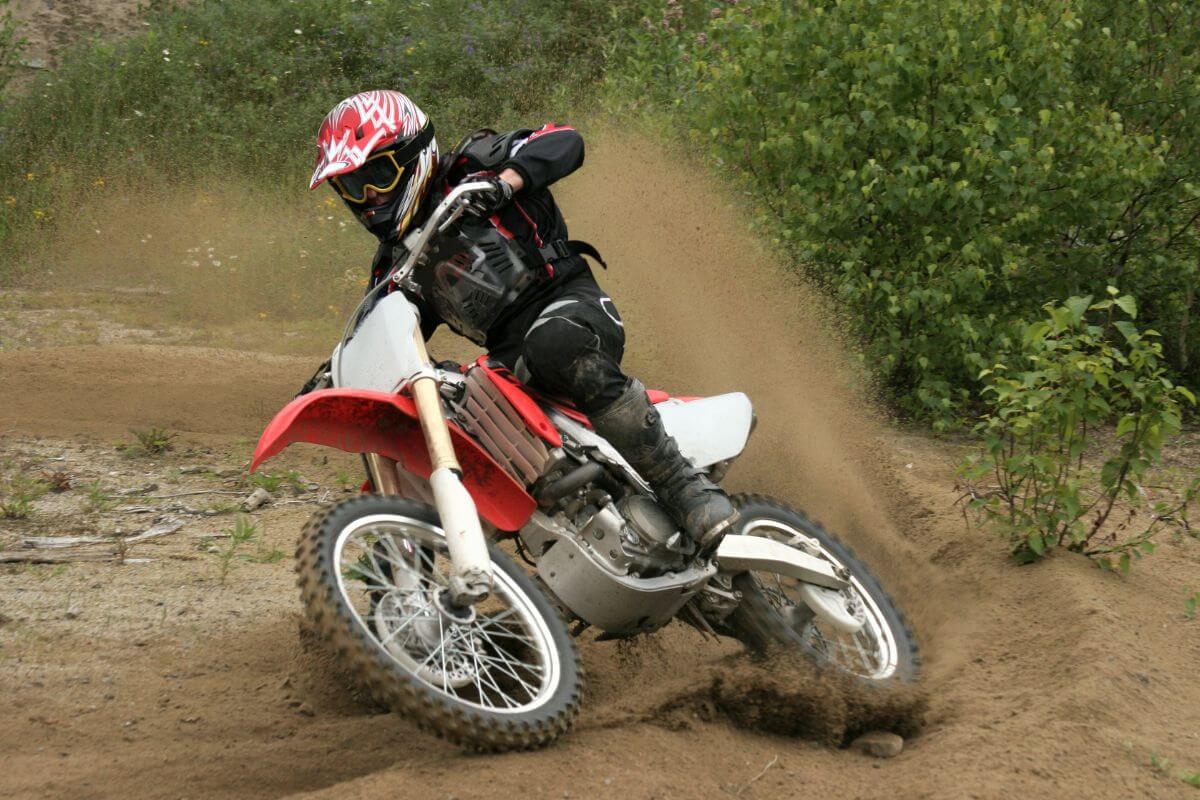 A motorcyclist kicks up dirt while taking an off-road turn during a Montana dirt bike tour.