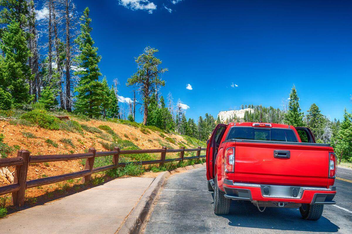 A red truck driving down a mountain road in Montana.