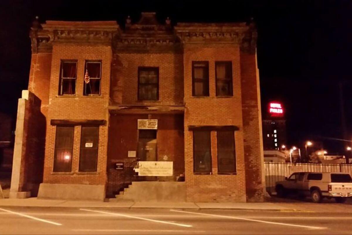 The Dumas Brothel building in Montana lives up to its eerie reputation, pictured with a car parked beside it at night.
