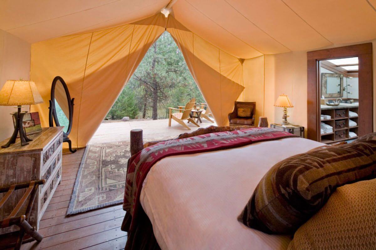 A cozy bedroom set up inside a tent, complete with a comfortable bed and a convenient bedside table, in Montana.