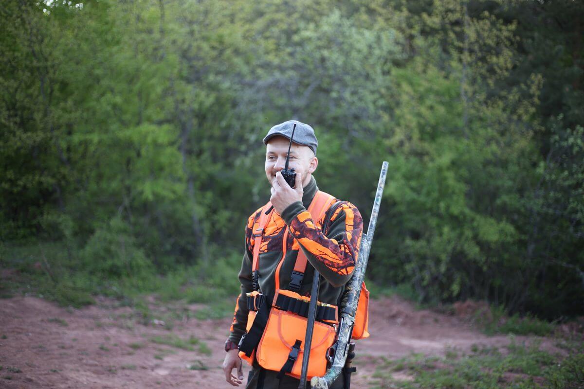 A hunter in a camouflage jacket and cap, following Montana hunting regulations by wearing the required hunter orange attire.