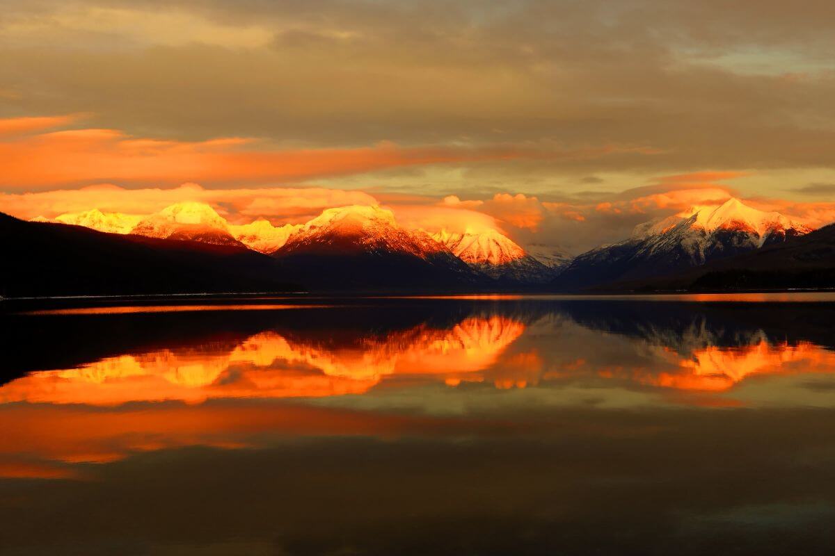 The enchanting Montana mountain range is reflected in a serene body of water during sunset.
