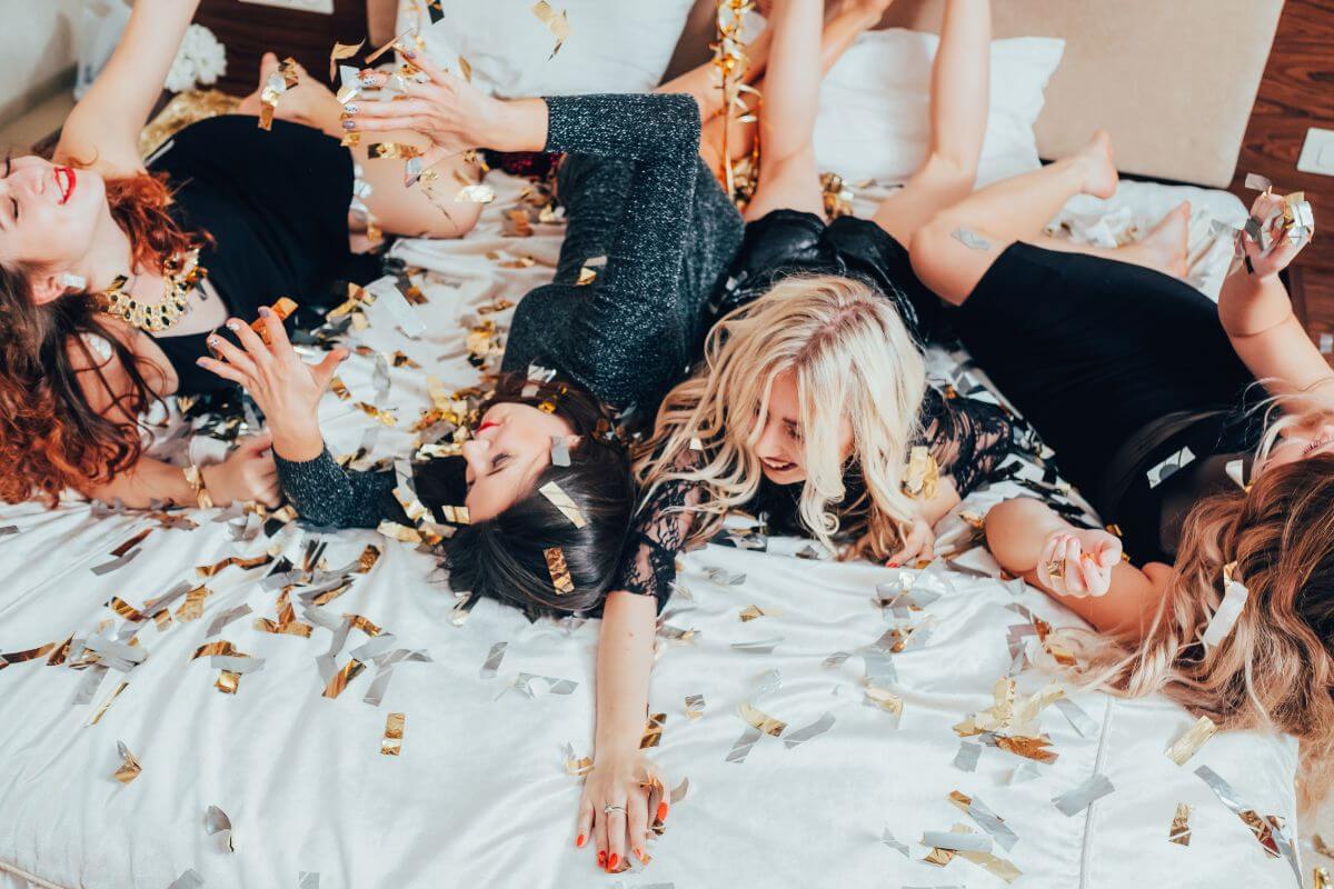 A group of women laying on a bed covered in confetti during a montana bachelorette party.