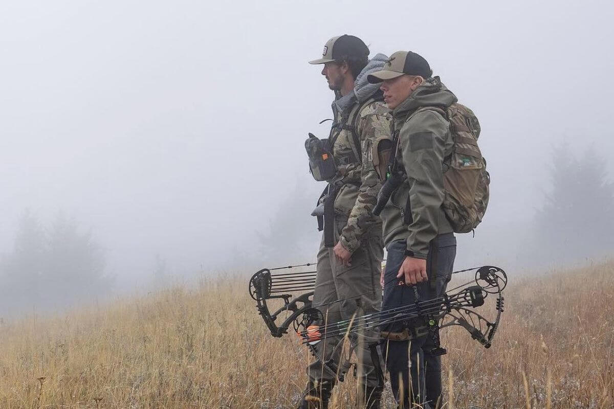 Two hunters standing in a foggy field in Montana with their hunting bows and arrows.