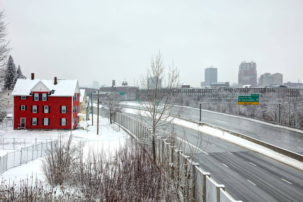 A red house on the side of a highway in New Hampshire surrounded by snow.