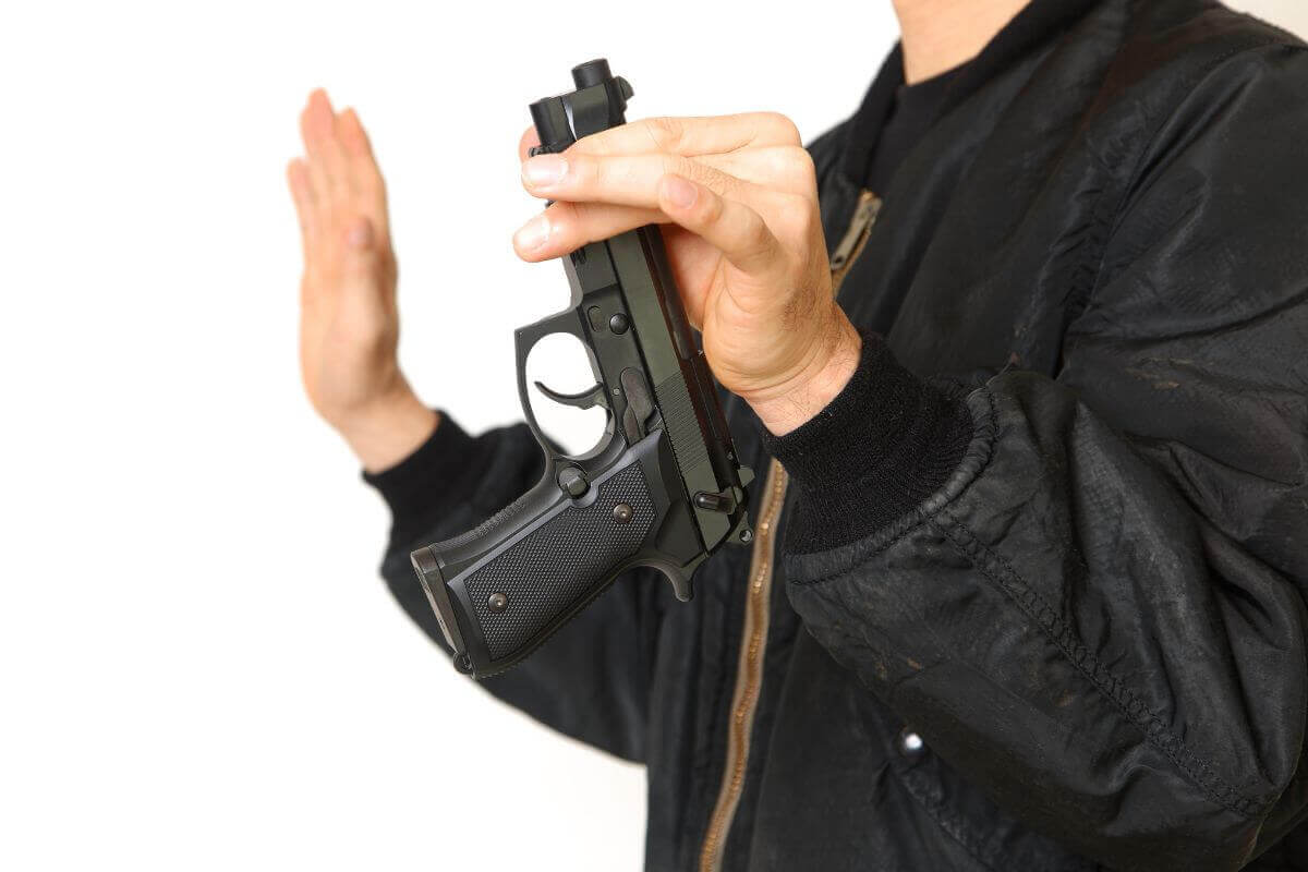 Man in a Black Jacket Holding Gun at the Tip