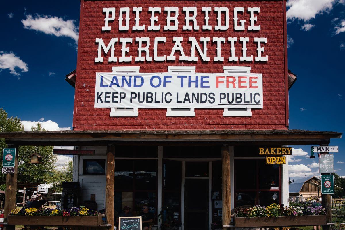 A wooden house with a big red sign on the roof showing Polebridge Mercantile in Montana.