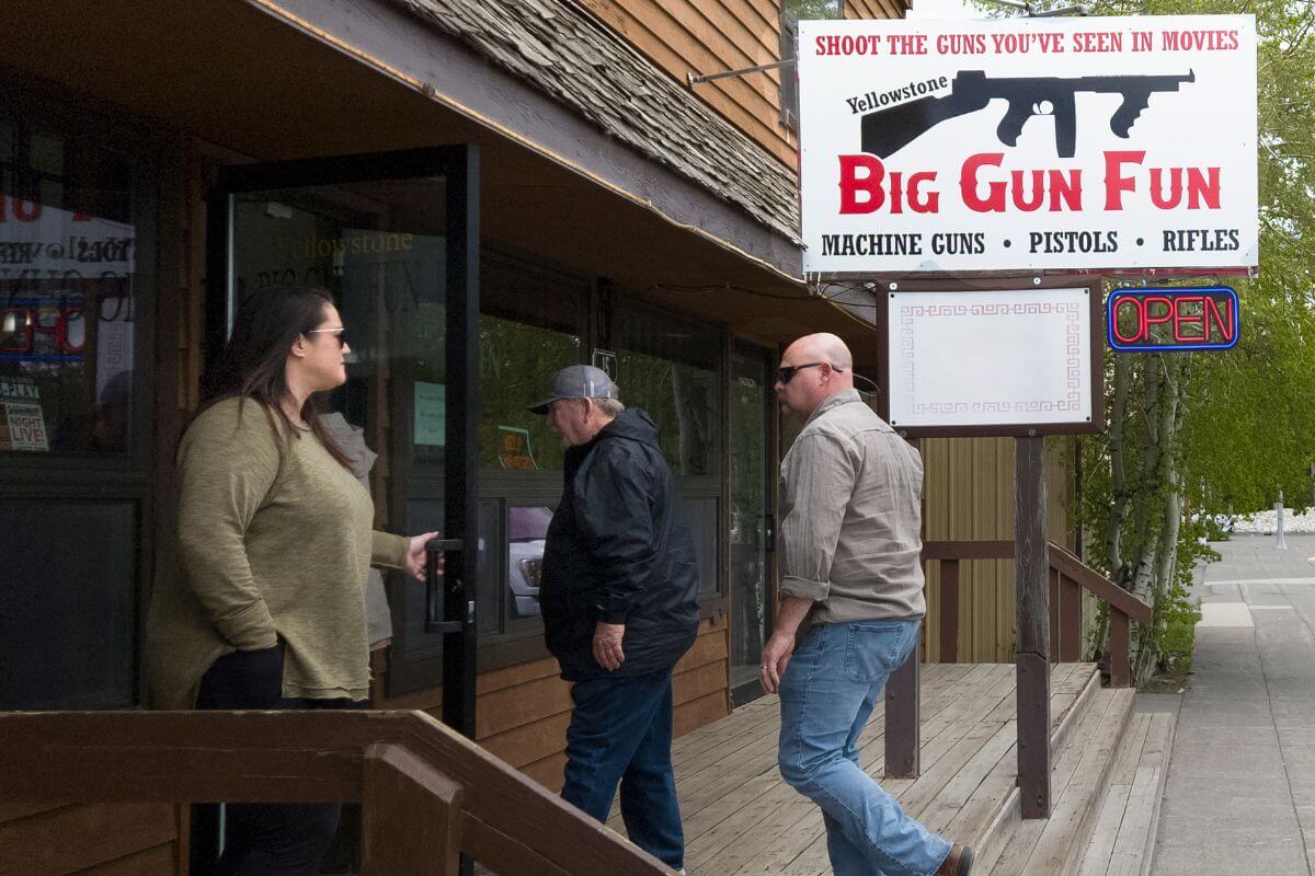 A woman holds the door open for two men entering Yellowstone Big Gun Fun, a gun store and "amusement park" in Montana for gun collectors and enthusiasts.