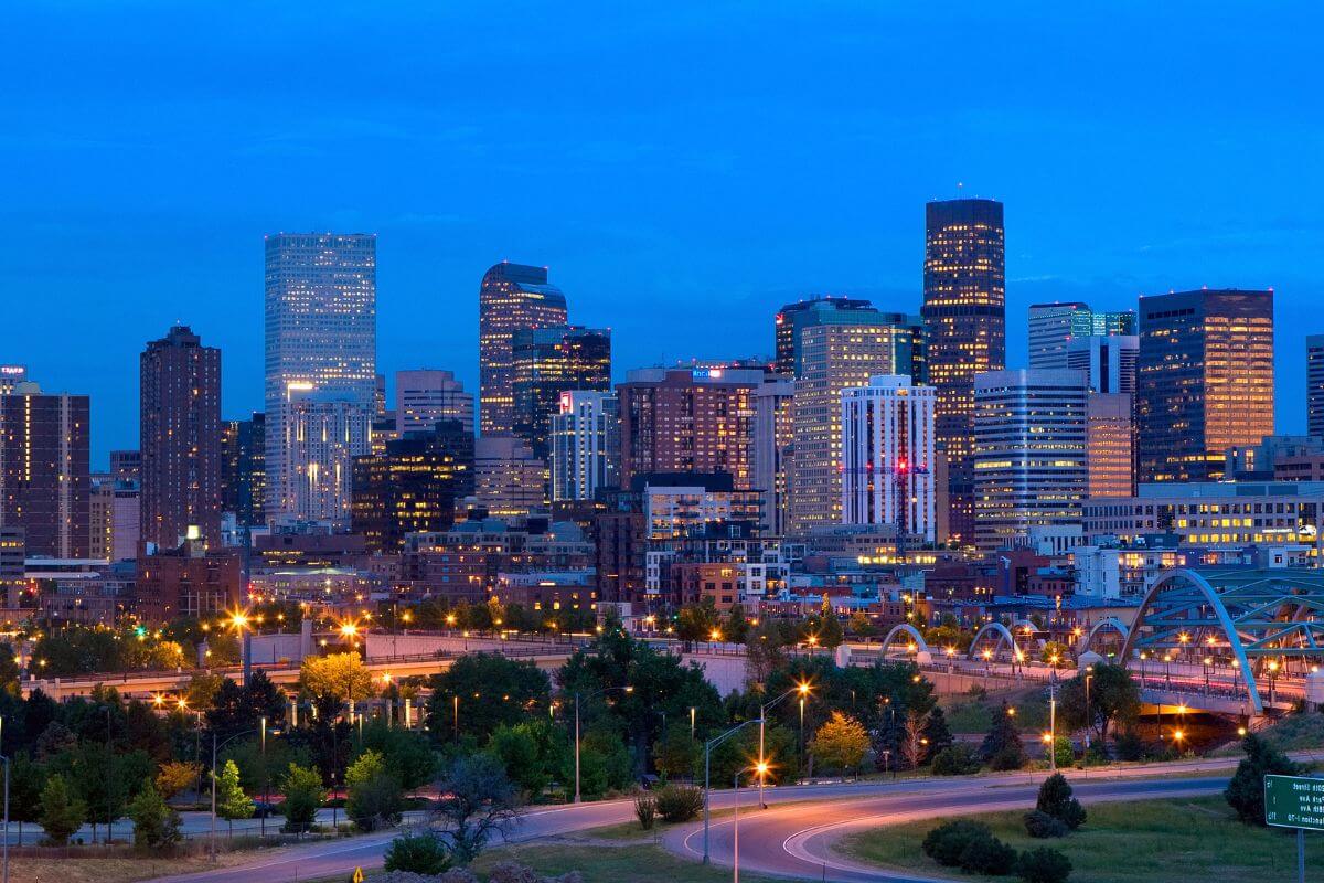 Colorado skyline at dusk showing skyscrapers with windows lit up.