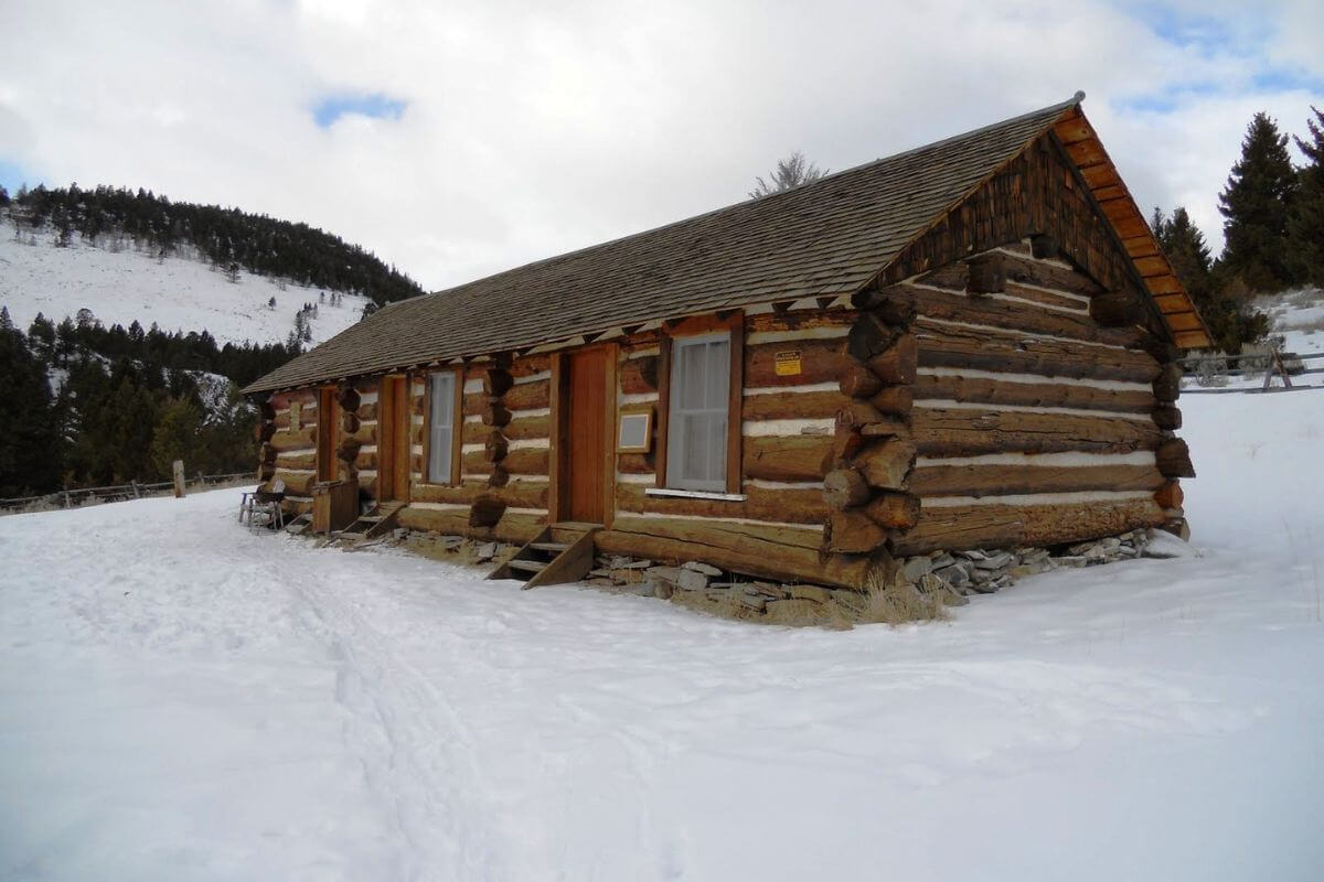 A cozy log cabin nestled in the snowy mountains of Montana in December.