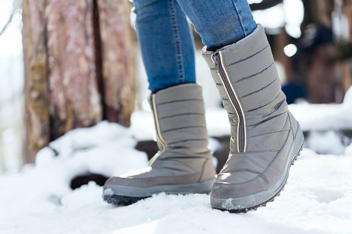 A person wearing tall gray winter boots in Montana's snow.
