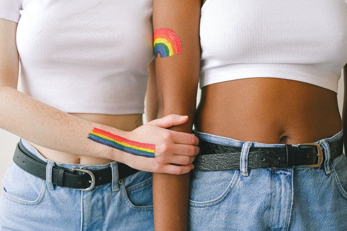 Two women linking arms with rainbow paint on their arms
