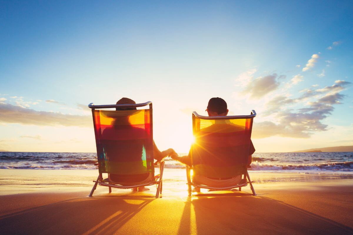 Two Retirees Sitting in Chairs on the Beach at Sunset