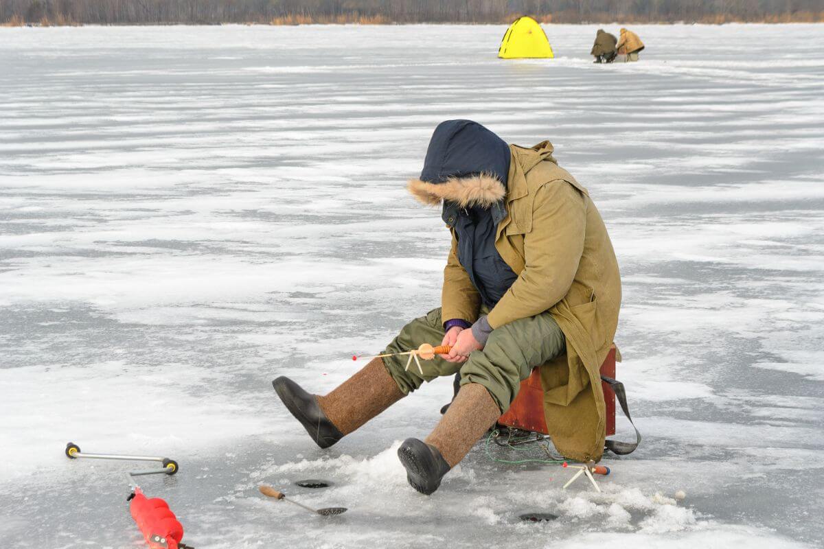 In the snowy state of Montana, a man braves the cold of January to enjoy a serene day ice fishing on a frozen lake.