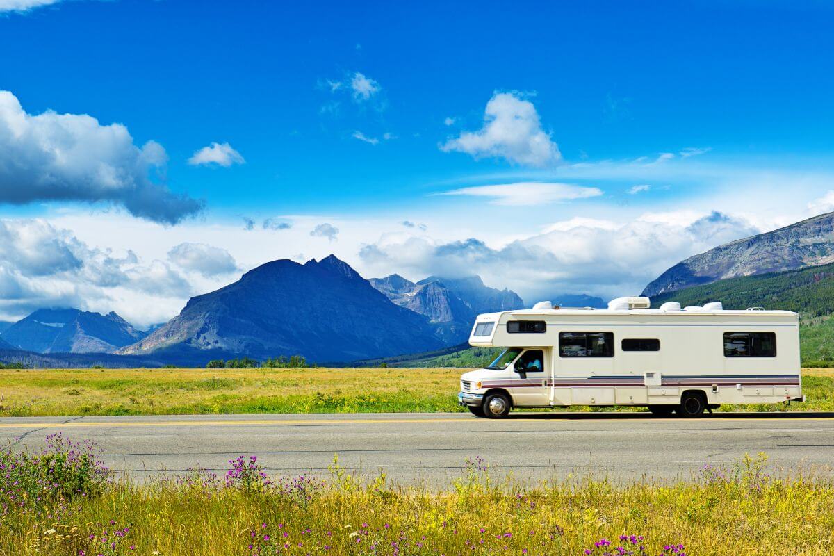 A white RV on a road with mountains in the background in Montana.