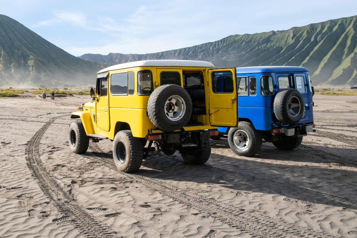 Yellow and blue off-road Jeeps parked on sandy terrain, ready for a jeep tour in Montana.