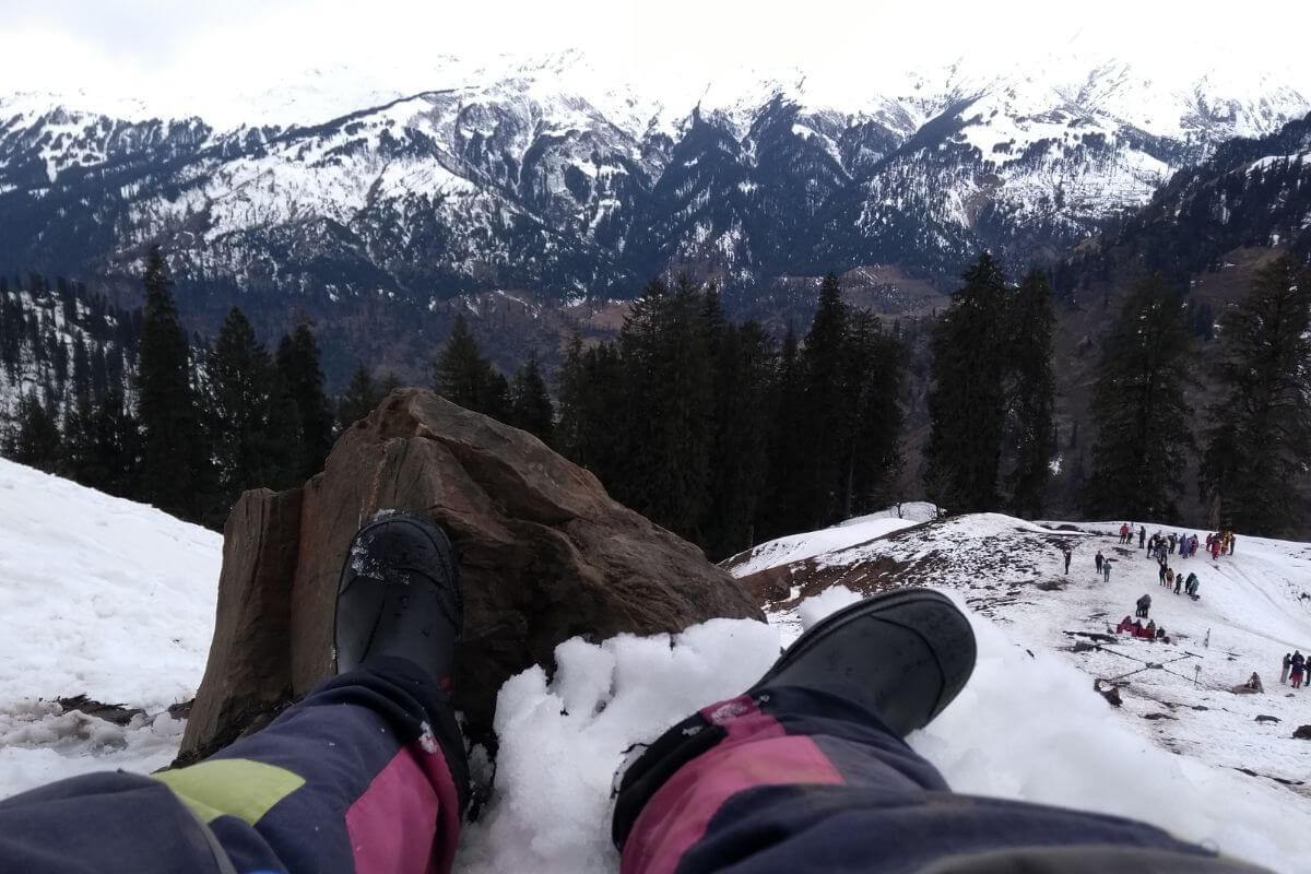 A person looks out from near the edge of a cliff wearing black winter boots
