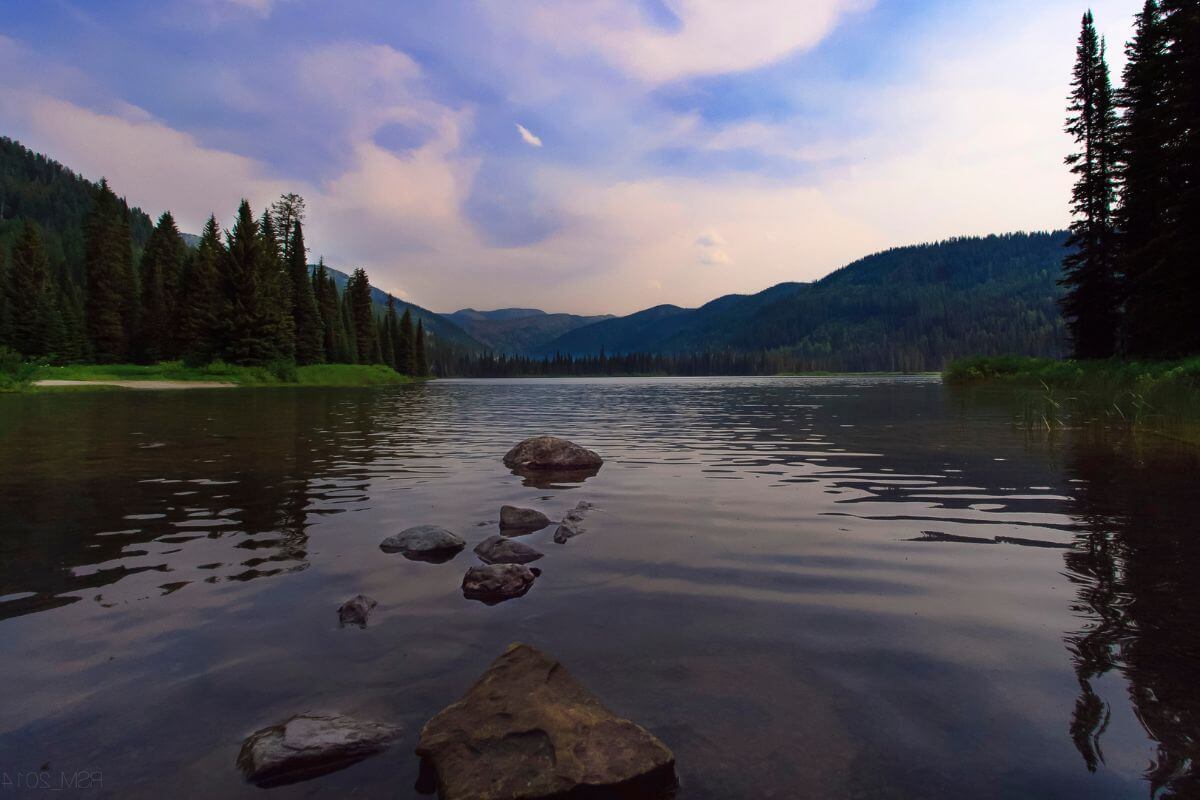 Whitefish Lake in Montana surrounded by rocks and towering trees.