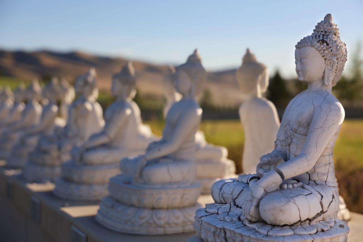A row of white buddha statues with mountains in the background