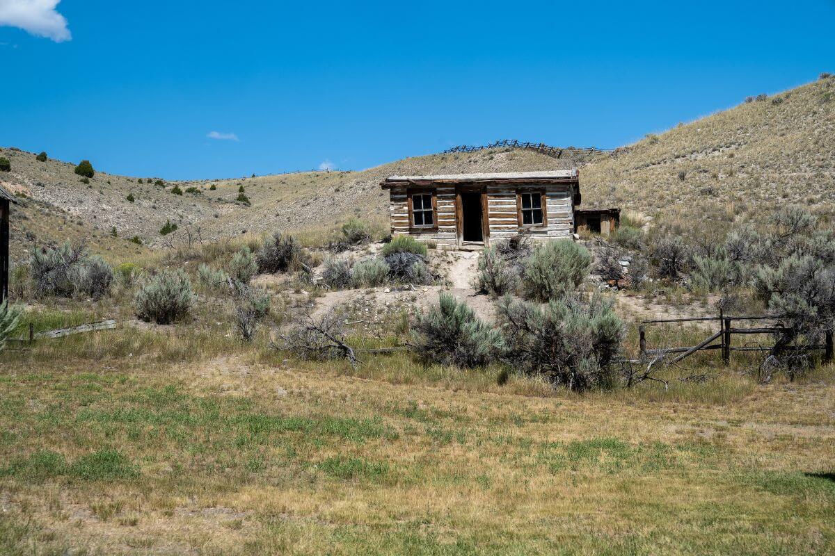 A solitary abandoned cabin in an elevated area of a grassy field in Montana perfectly embodies the state's haunted sites.