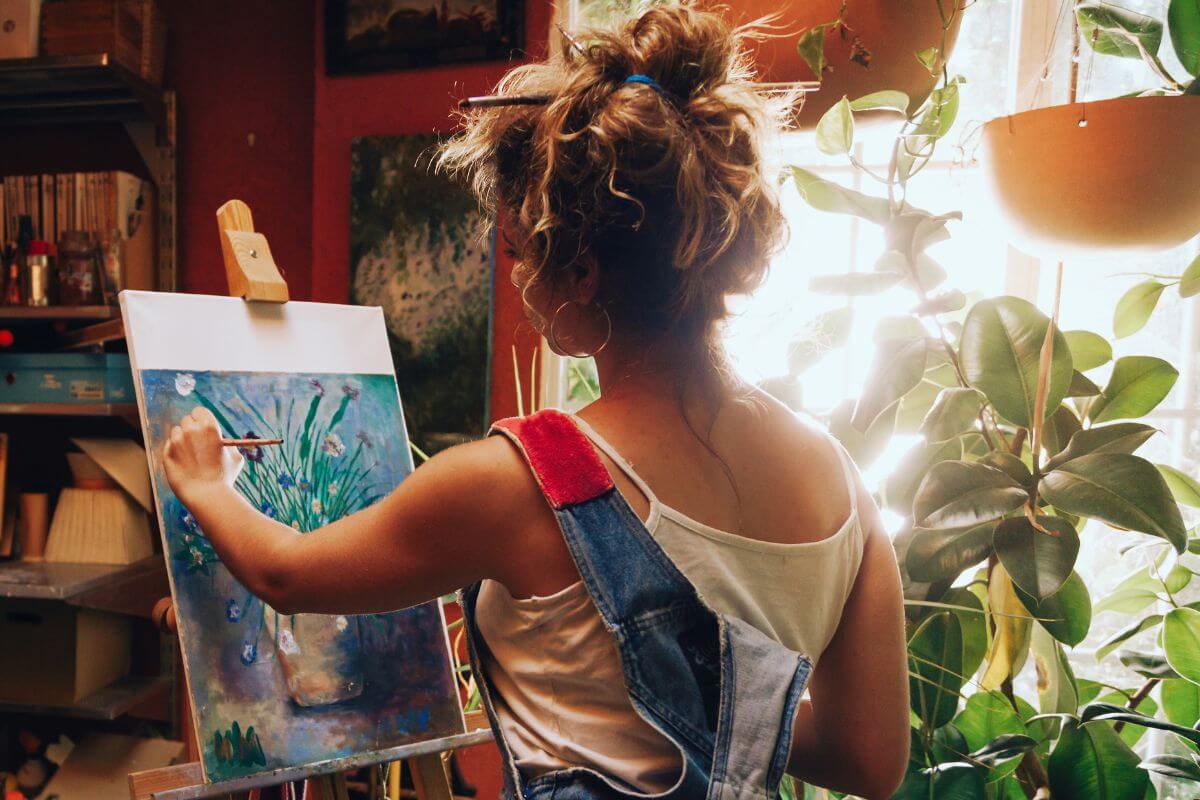 A woman is painting on an easel in an art studio with Montana gemstones.