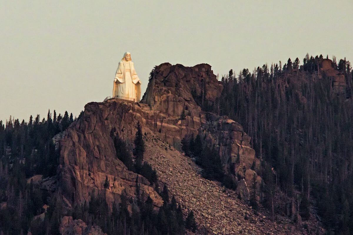 A magnificent white statue sits on top of a majestic mountain, offering breathtaking views for those seeking the best Montana vacations.