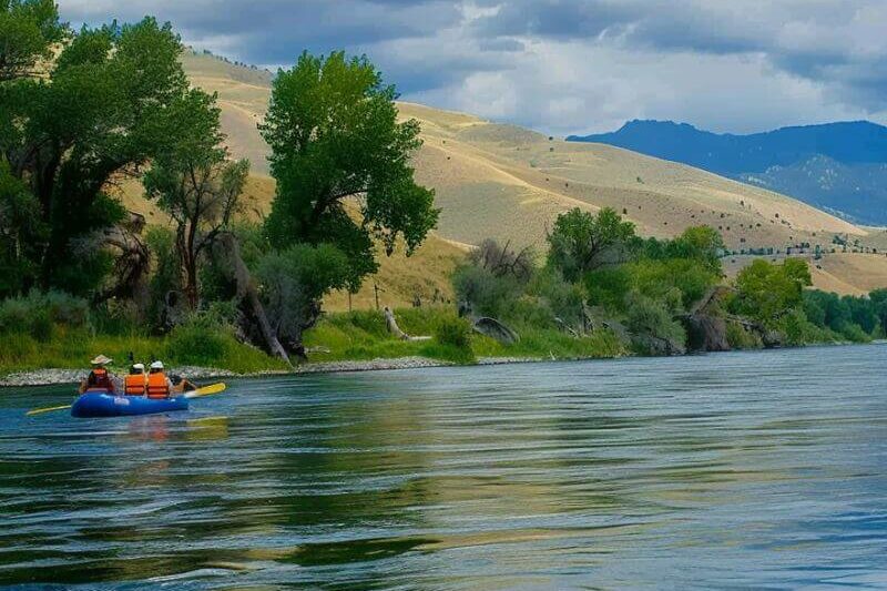 A group of people rafting down a river with mountains in the background in Montana.