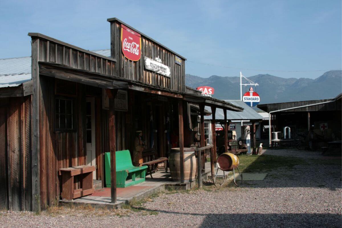 A wooden building in The Miracle of America Museum with a view mountains in the background in Montana.