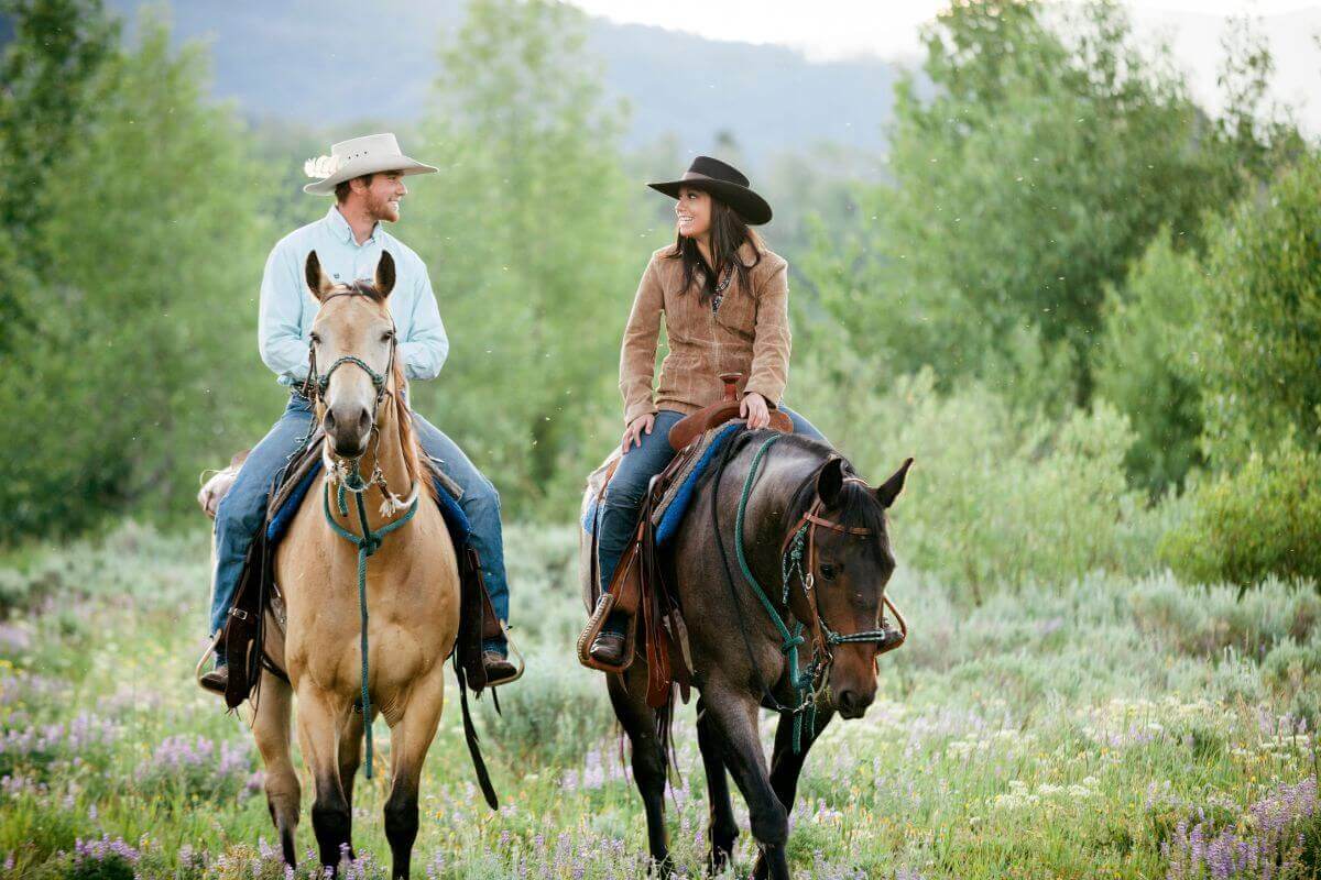 A man and woman horseback riding in a Montana field.