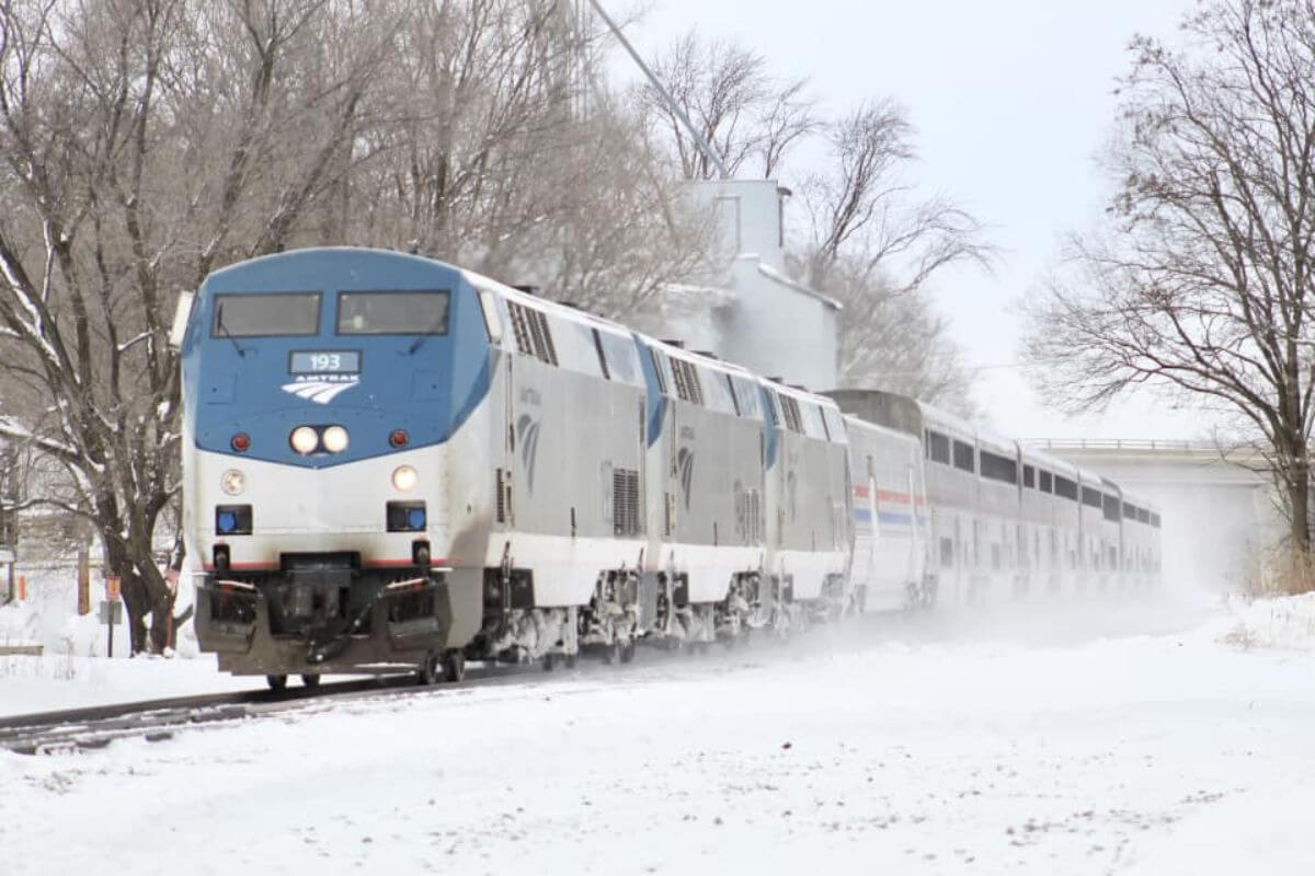 An Amtrak train called the Empire Builder powering through a snowy landscape, one of the best Montana train tours.