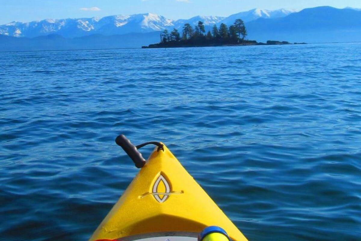 The tip of a yellow kayak on a calm blue lake near Miche Wabun Falls